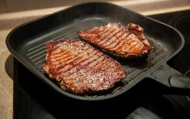 Raw minute steak of marbled beef in a grill pan close up
